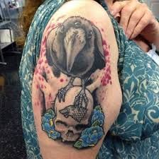 Ptak stojący na czaszce tatuaż