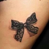 Tatuaż na udzie z kokardą