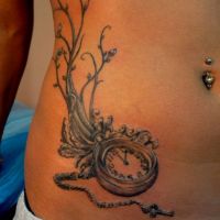Zegar z gałązką tatuaż na brzuchu